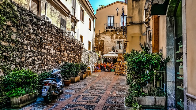 Traditional Italian restaurant street scene with outdoor seating and a scooter in a narrow alley